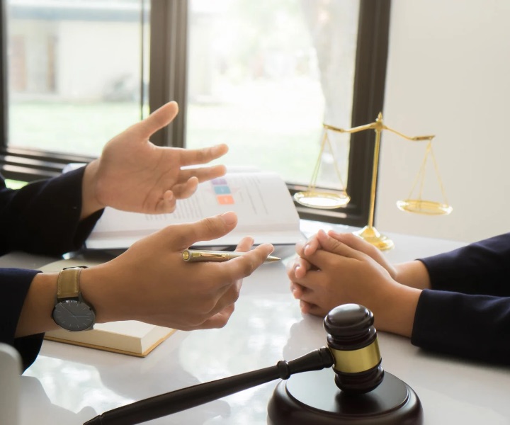 Lawyers discussing a signed agreement across a desk with scales of justice and a gavel